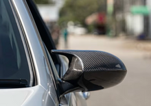Car side mirror with carbon fiber finish on a blurred street background
