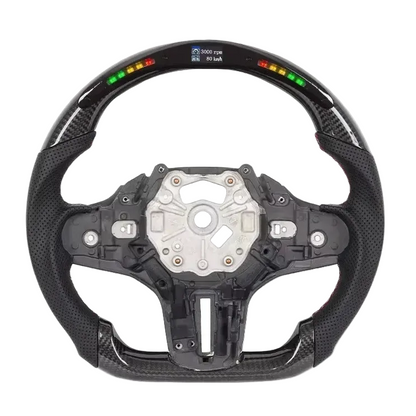 A carbon fiber racing-style steering wheel with a digital display showing battery percentage and RPM, isolated on a white background.